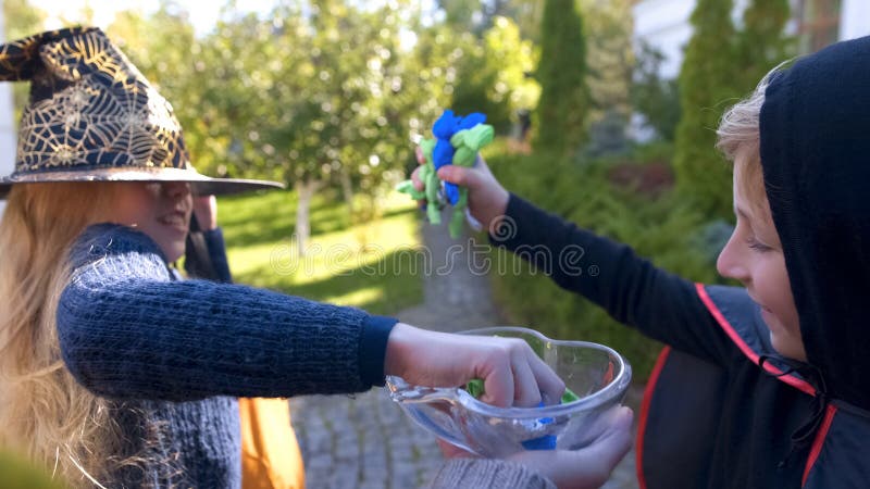 Glad flicka och pojke som tar alla gränsa till godisar som trick-eller-behandlar på allhelgonaafton royaltyfri bild Glad flicka och pojke som tar alla gränsa till godisar som trick-eller-behandlar på allhelgonaafton royaltyfri bild