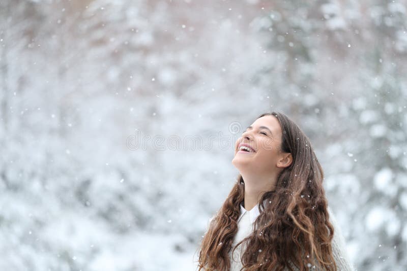 Glad flicka som andas frisk luft och njuter av snö på vintern