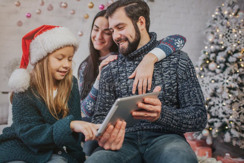 Glad jul och lyckliga ferier gladlynt mamma, farsa och hennes gulliga dotterflicka som använder en flatbedPC Förälder och lite royaltyfri fotografi