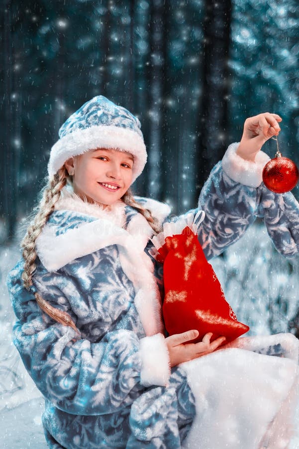 Glad jungfru i festlig dräkt lilla flickan är le och rymma nytt års leksak och påse med gåvor glad vinterskog royaltyfria foton Glad jungfru i festlig dräkt lilla flickan är le och rymma nytt års leksak och påse med gåvor glad vinterskog royaltyfria foton