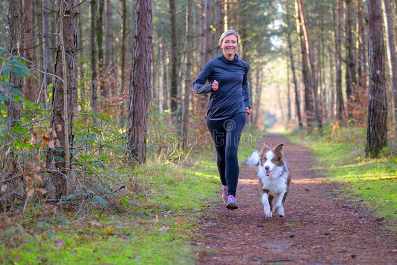 Glad kvinna full av livskraft när hon tränar sin hund fotografering för bildbyråer