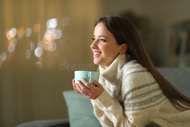 Glad kvinna som håller kaffekopp hemma på vintern arkivfoto