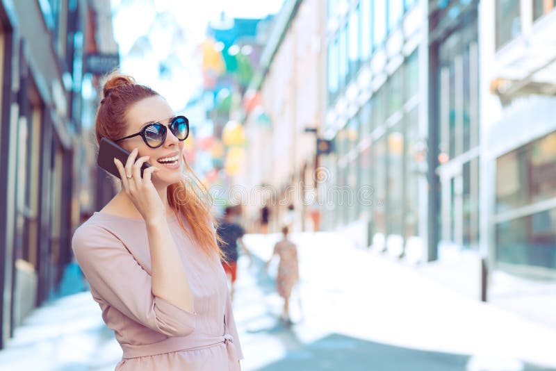 Glad kvinna som ringer på en mobiltelefon som ser bort från gatan