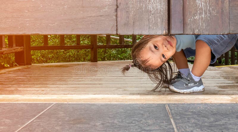 Glad liten flicka från Asien spelar peekaboo under trädörren i trädgården royaltyfria bilder Glad liten flicka från Asien spelar peekaboo under trädörren i trädgården royaltyfria bilder