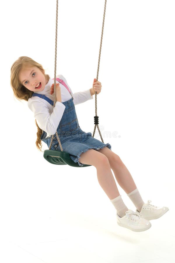 Glad liten flicka skolflicka som svänger på en sväng. fotografering för bildbyråer