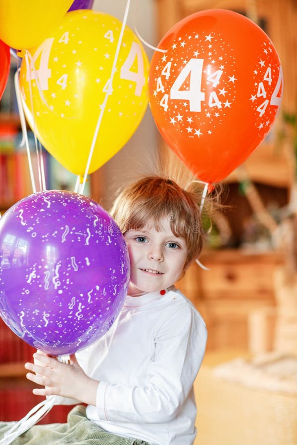 Glad liten förskolepojke som firade sin 4-årsdag med färgfulla ballonger inomhus i kidsrum. Uppspelat barn royaltyfri bild