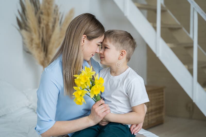 Glad mammor dag! Den lilla son ger blommor till mamma-pojken gratulerar blommorna i händerna på en pojke gul daffodils glad arkivfoto