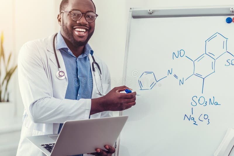 Glad millennial medicinsk professionell som pekar in mot kemisk formel royaltyfria foton Glad millennial medicinsk professionell som pekar in mot kemisk formel royaltyfria foton