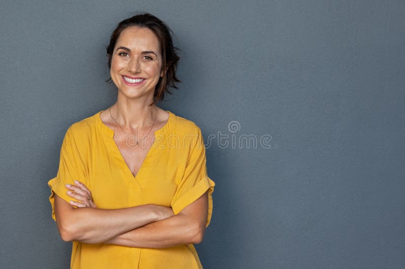 Glad mogen kvinna som ler på grå vägg royaltyfri fotografi