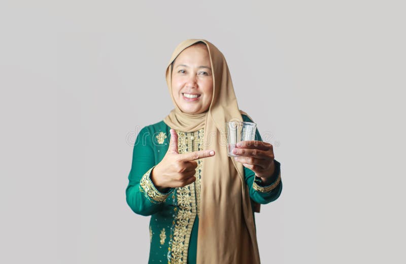 Glad muslimsk kvinna i traditionell utsmyckning vid ett glas vatten arkivbilder