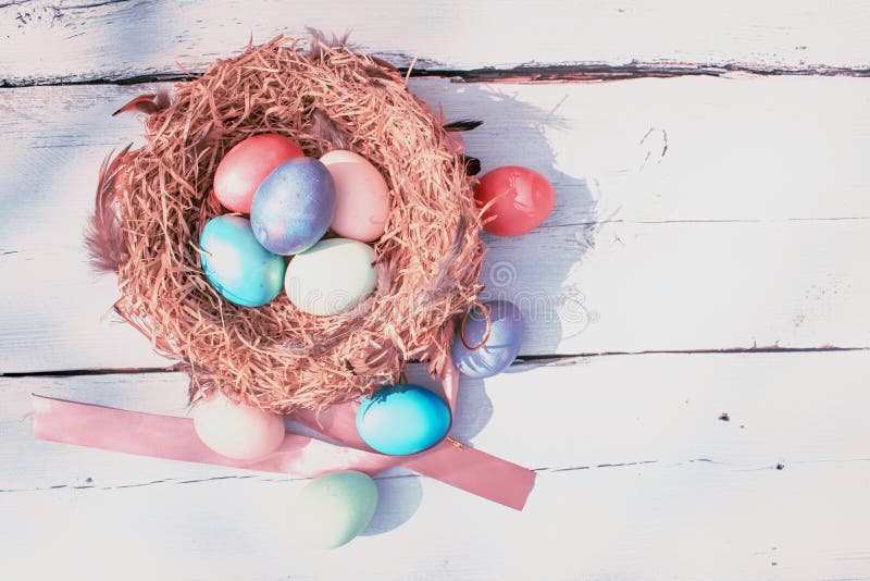 Glad påsk Färgfyllda Easters-ägg i ett bo med fjädrar på baksidan av trä fotografering för bildbyråer Glad påsk Färgfyllda Easters-ägg i ett bo med fjädrar på baksidan av trä fotografering för bildbyråer