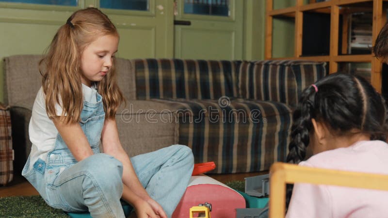 Glad tjej som leker leksak med olika barn medan de sitter i lekrummet. uppgörelse. lager videofilmer