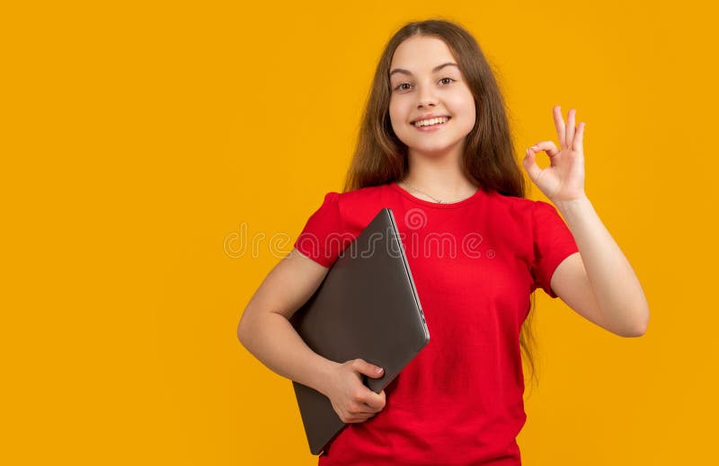 Glad tonåring med bärbar dator med gul bakgrund. ok