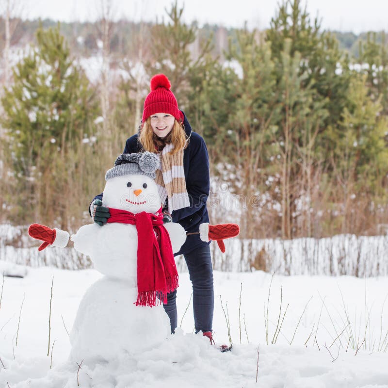 Glad tonåring med snowman i vinterskog arkivfoton Glad tonåring med snowman i vinterskog arkivfoton