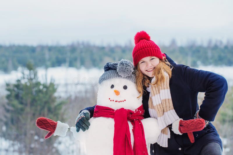 Glad tonåring med snowman i vinterskog royaltyfri fotografi Glad tonåring med snowman i vinterskog royaltyfri fotografi