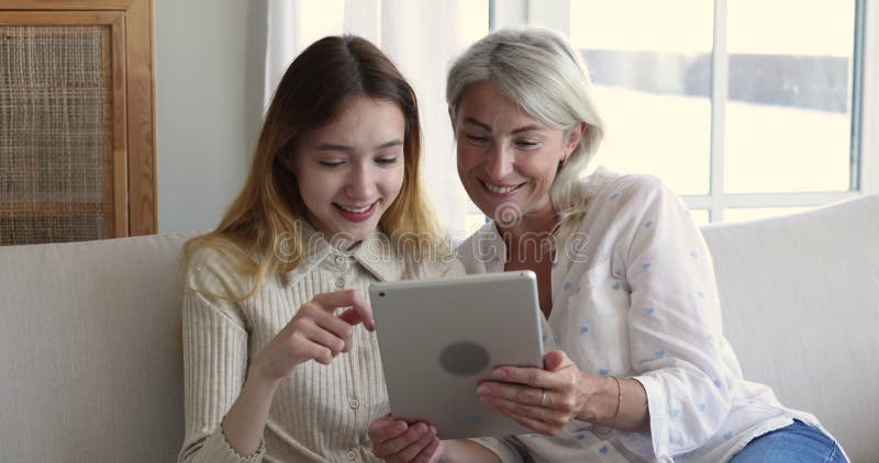 Glad tonårsflicka och glad mormor som använder pekdator