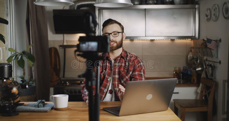 Glad ung framgångsrik kaukasisk professionell bloggare som leker med att spela upp video med kamera i hemmet med långsam rörelse