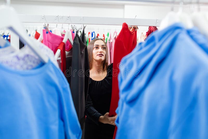 Glad ung kvinna som väljer kläder i köpcentra eller i klädesplagg Försäljning, mode, konsumtionskoncept fotografering för bildbyråer