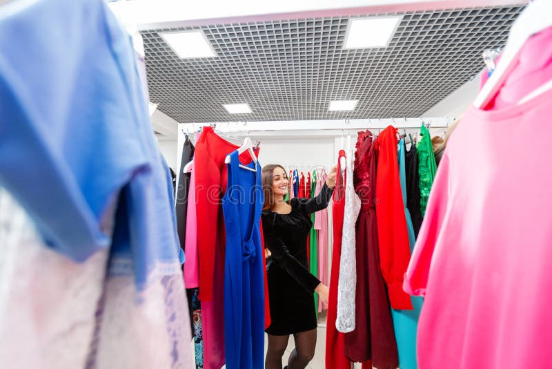 Glad ung kvinna som väljer kläder i köpcentra eller i klädesplagg Försäljning, mode, konsumtionskoncept fotografering för bildbyråer