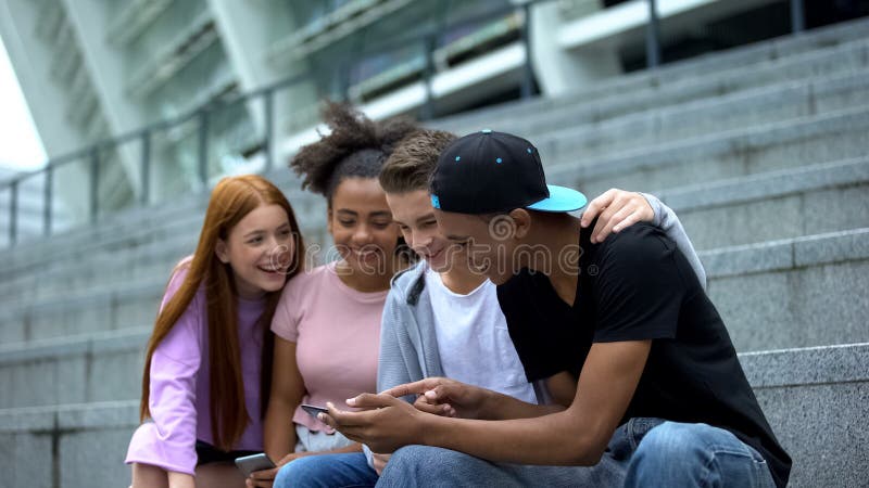 Glad universitetsstudent som tittar på video online med smartphone och har kul, gadget royaltyfri foto
