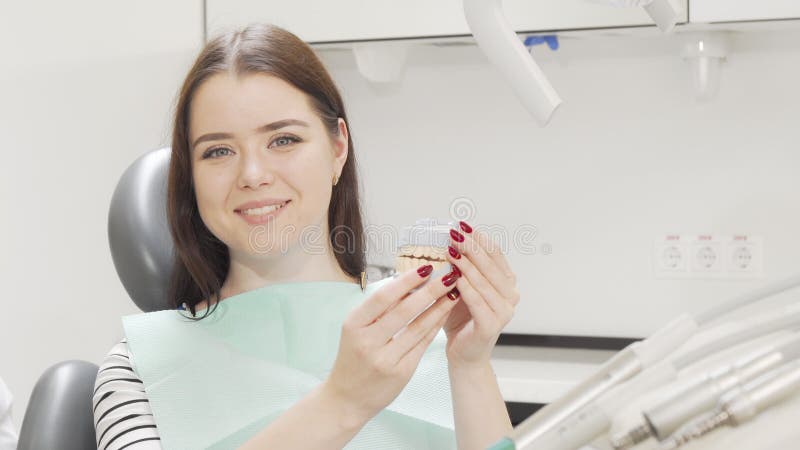 Glad, vacker kvinna med tandläkarmodell som ler mot kameran