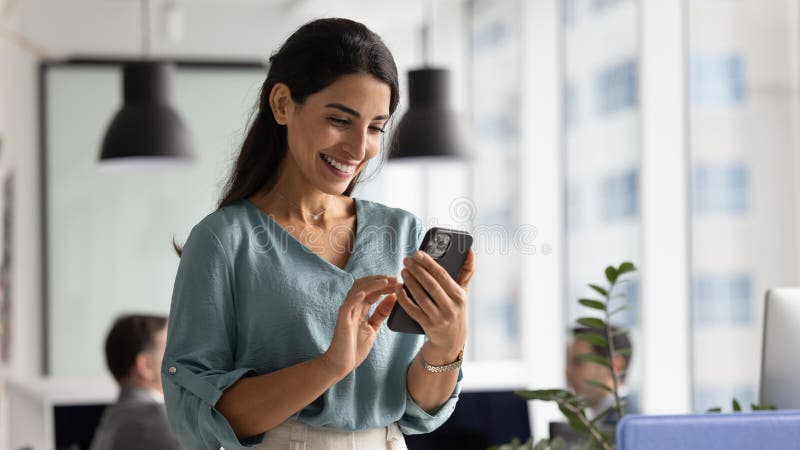 Glad, vacker, latinsk affärskvinna som använder webbtjänst på smartphone arkivfoton