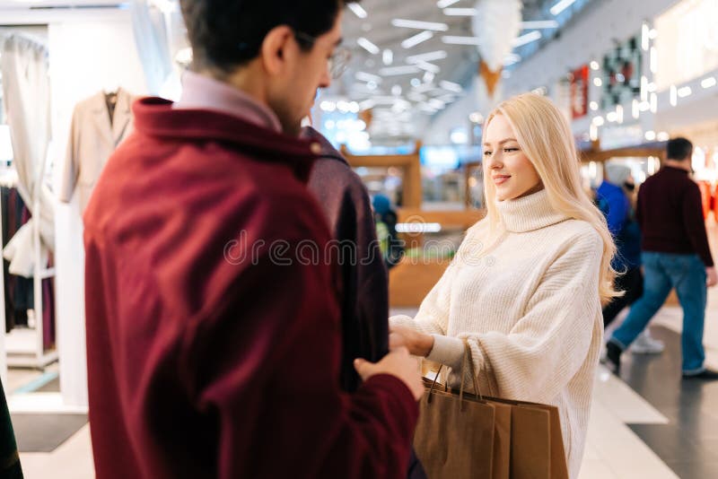 Glada unga par som väljer kläder tillsammans i klädesbutiken på shoppingcentret. blond kvinna som väljer kvinnlig rock med royaltyfri foto