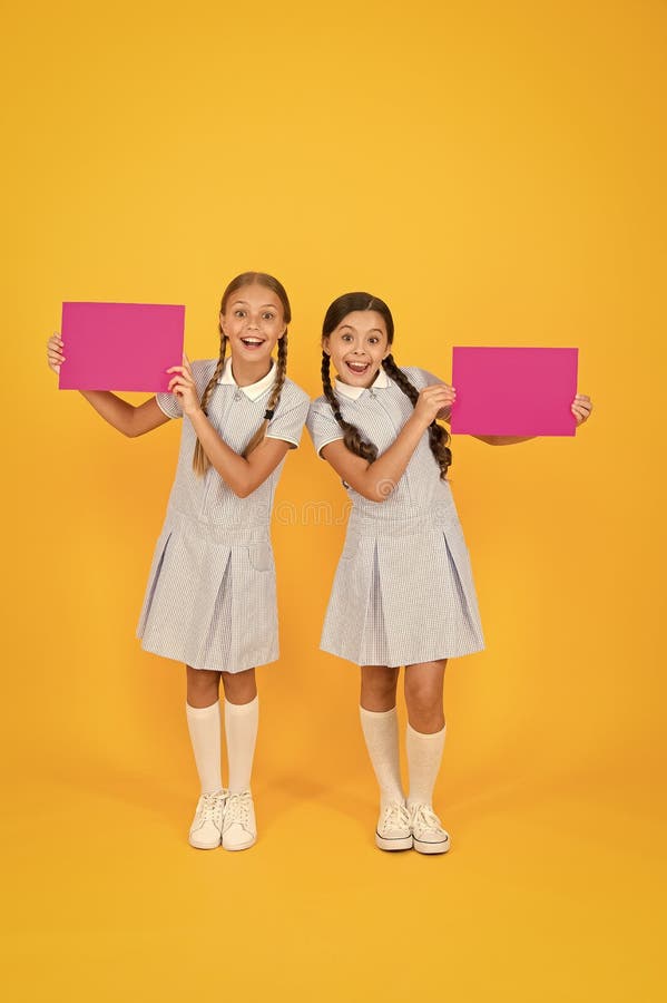 Glada vänner i återo-uniform. årgång. tillbaka till skolan. små flickor har blankpapper. Encyklopedia-bok för