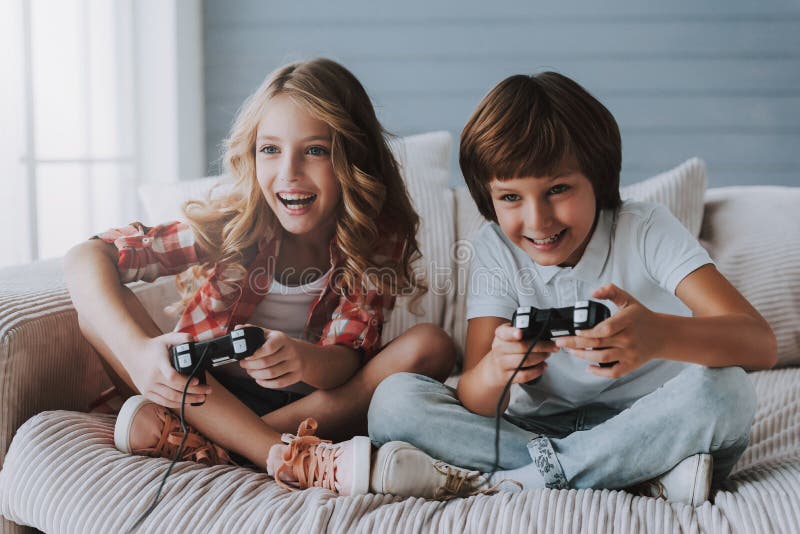 Glade barn med modiga kontrollanter spelar videospel hemma arkivfoto Glade barn med modiga kontrollanter spelar videospel hemma arkivfoto