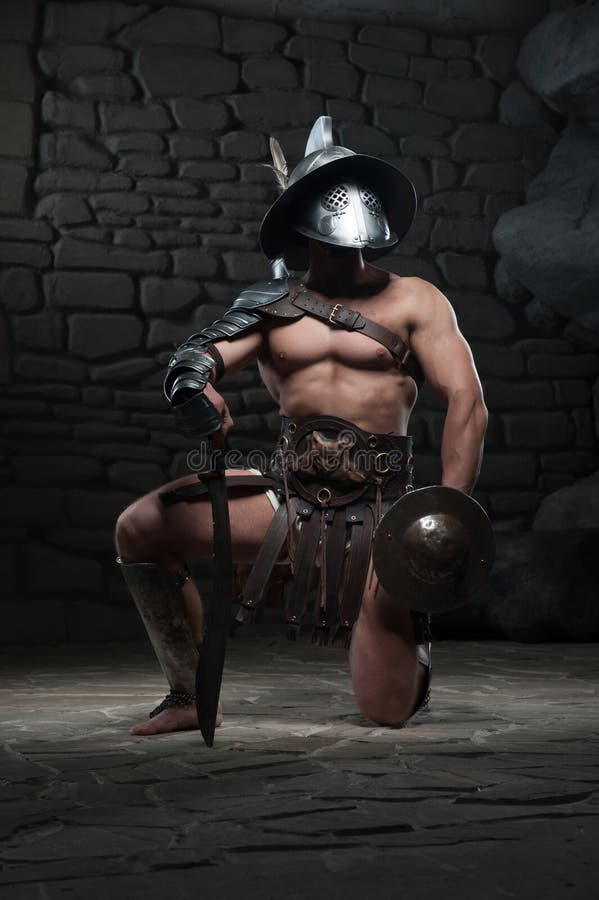 Gladiador no capacete e armadura que guarda a espada foto de stock royalty free Gladiador no capacete e armadura que guarda a espada foto de stock royalty free