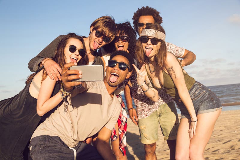 Gladlynta multietniska vänner som tar selfie på stranden på solig dag royaltyfri bild Gladlynta multietniska vänner som tar selfie på stranden på solig dag royaltyfri bild
