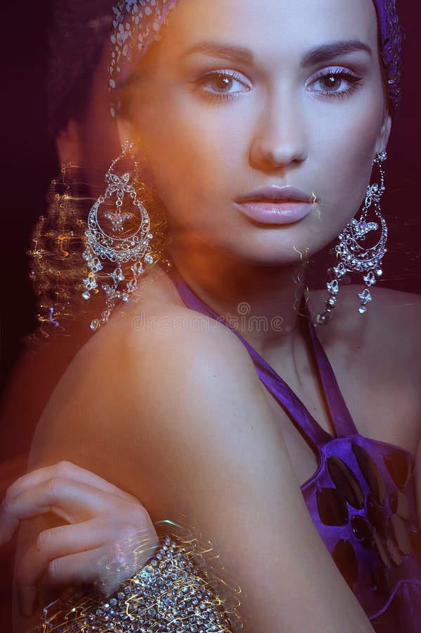 Glamor girl in beautiful jewelry motion blur. Closeup portrait glamor girl in violet evening dress and beautiful jewelry in motion blur