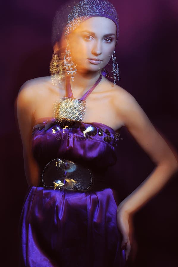 Portrait glamor girl in violet evening dress and beautiful jewelry in motion blur. Portrait glamor girl in violet evening dress and beautiful jewelry in motion blur