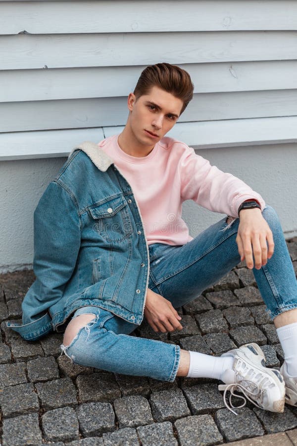 Glamorous trendy young man in ripped jeans in blue denim jacket