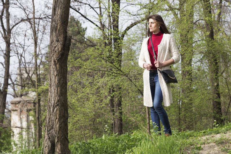 Charming young woman in white cardigan. Shooting has been in the spring city within the Roses Valley Park. Charming young woman in white cardigan. Shooting has been in the spring city within the Roses Valley Park