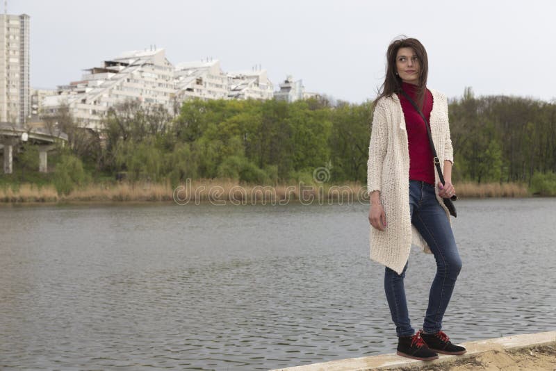 Charming young woman in white cardigan. Shooting has been in the spring city within the Roses Valley Park. Charming young woman in white cardigan. Shooting has been in the spring city within the Roses Valley Park