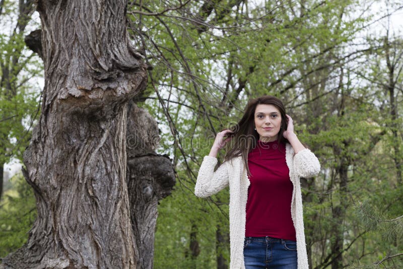 Charming young woman in white cardigan. Shooting has been in the spring city within the Roses Valley Park. Charming young woman in white cardigan. Shooting has been in the spring city within the Roses Valley Park