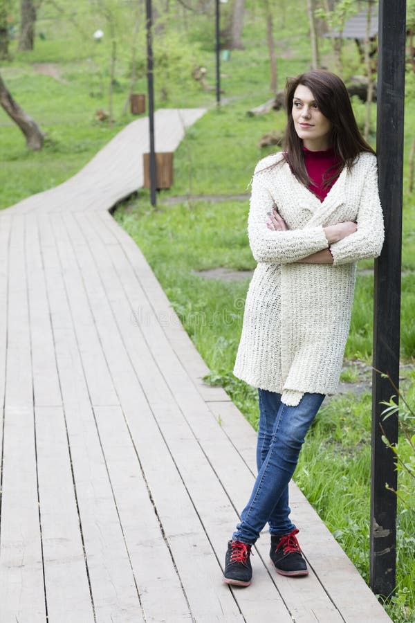 Charming young woman in white cardigan. Shooting has been in the spring city within the Roses Valley Park. Charming young woman in white cardigan. Shooting has been in the spring city within the Roses Valley Park