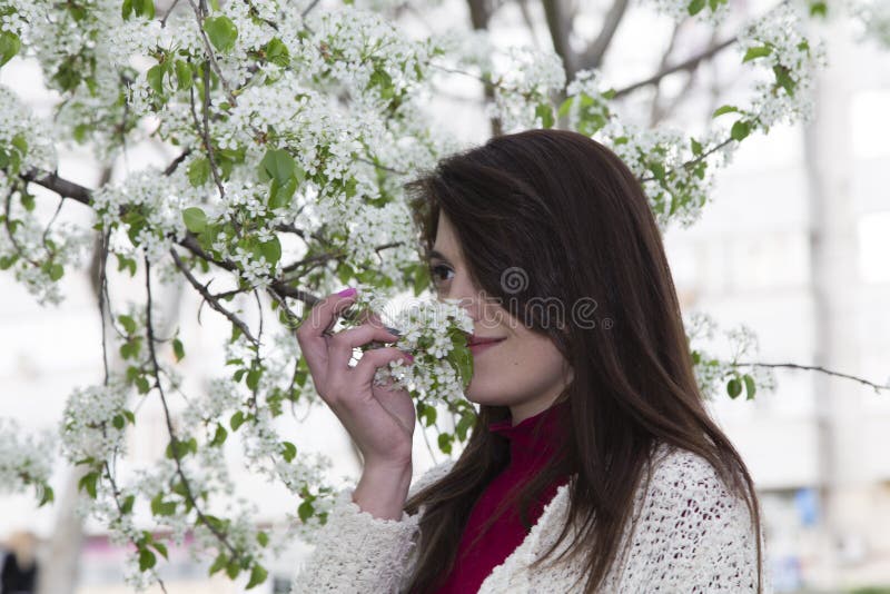 Charming young woman in white cardigan. Shooting has been in the spring city within the Roses Valley Park. Charming young woman in white cardigan. Shooting has been in the spring city within the Roses Valley Park