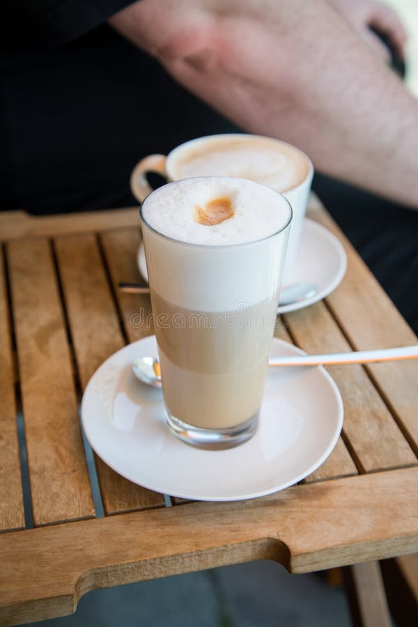 Glas De Latte Macchiato Et Tasse De Cappuccino CafÃ© Avec Du Lait Sur Table  En Bois Ã L'extÃ©rieur Du Caf De Rue Photo stock - Image du glace, crème:  156693926