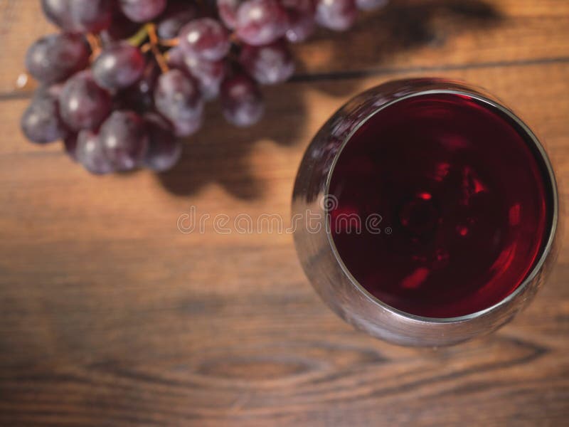 Glas Rotwein in der Fokusgruppe von frischen roten Trauben auf einem Holztisch aus Draufsicht Fokus heraus lizenzfreie stockfotografie