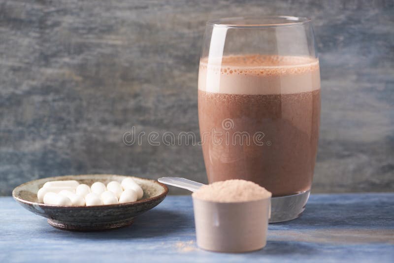 Glas van Chocolade Eiwitschok met melk en banaan Weiprote?ne in lepel en BCAA-aminozuren op achtergrond