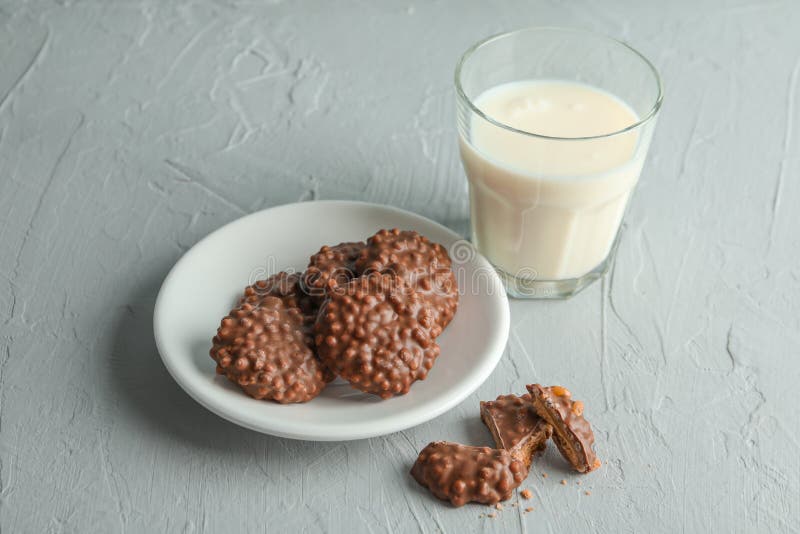 Glas van melk en plaat met chocoladekoekjes op grijze lijst stock fotografie Glas van melk en plaat met chocoladekoekjes op grijze lijst stock fotografie