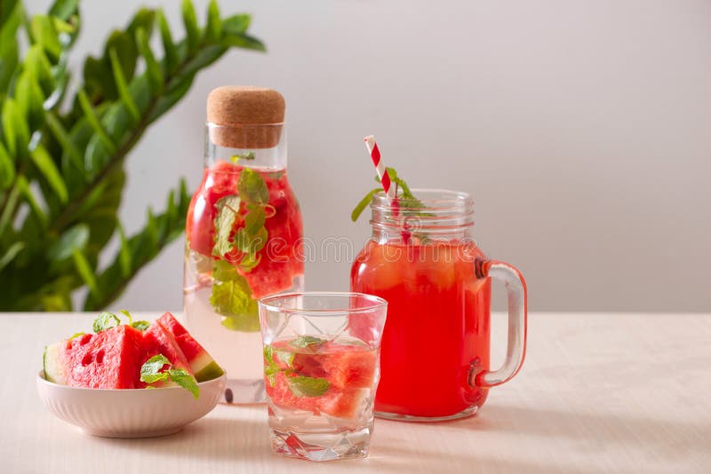 Glas vers rood watermeloensap op lijst in keuken Rijpe watermeloenen en plakken op achtergrond stock foto's Glas vers rood watermeloensap op lijst in keuken Rijpe watermeloenen en plakken op achtergrond stock foto's
