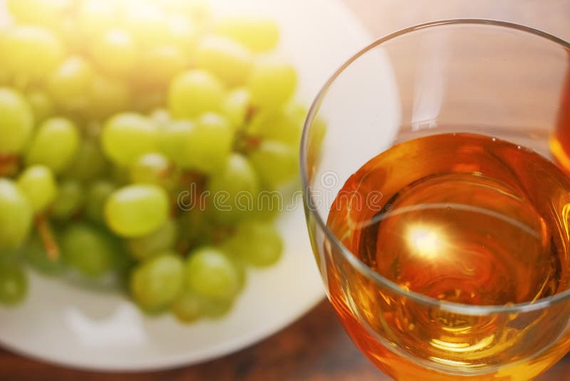 Glas Wein in der Fokusgruppe von frischen Grüne Trauben aus Sonnen-Aufflackernstillleben Fokus aus warmem stockfotografie