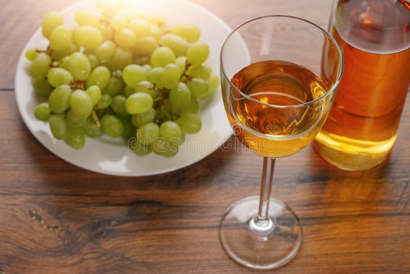 Glas Weißwein in der Fokusflasche Wein und in der Gruppe von frischen Trauben auf einer weißen Jury unscharf lizenzfreie stockfotografie