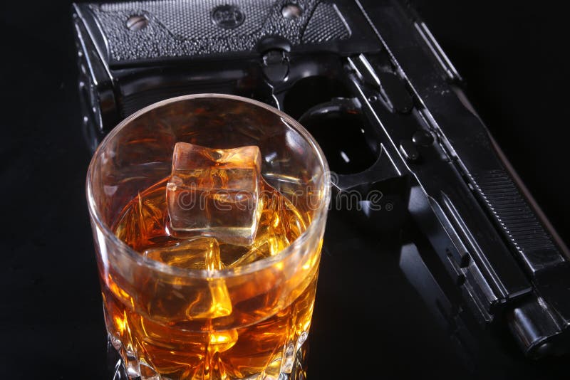 Glas whisky of cognac en kanon op de zwarte spiegellijst Het concept misdadiger stock afbeeldingen Glas whisky of cognac en kanon op de zwarte spiegellijst Het concept misdadiger stock afbeeldingen