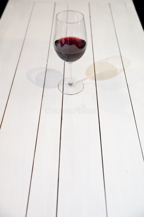 GLAS OF WINE ON WHITE WOODEN TABLE royalty free stock photo