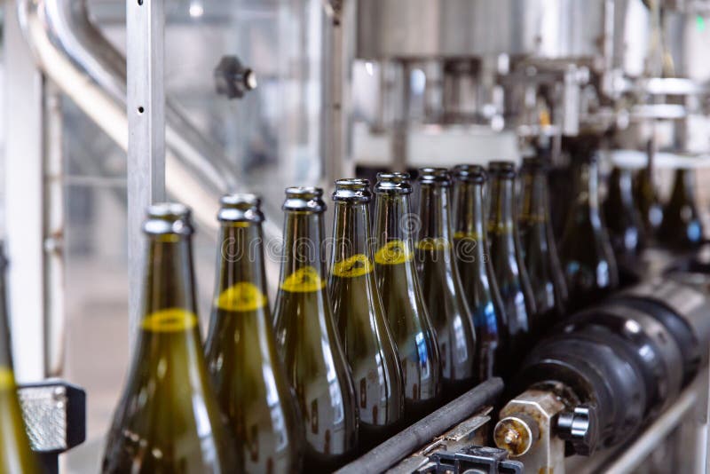 Glasflaskor på den automatiska transportörlinjen på champagne- eller vinfabriken Växt för att buteljera alkoholdrycker