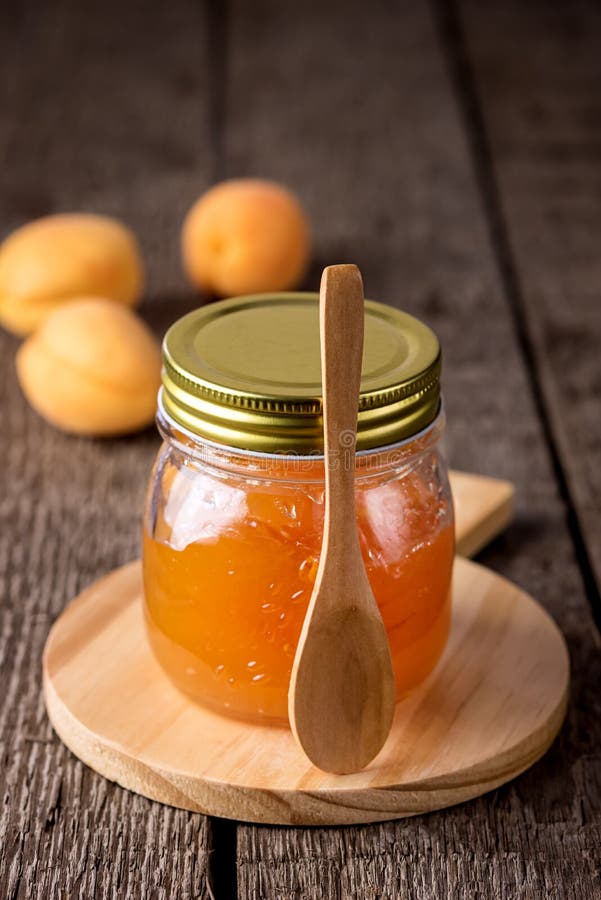 Glasgefäß selbst gemachte geschmackvolle Aprikosen-Marmelade und reife Aprikosen auf der hölzernen Hintergrund-Vertikale lizenzfreie stockbilder Glasgefäß selbst gemachte geschmackvolle Aprikosen-Marmelade und reife Aprikosen auf der hölzernen Hintergrund-Vertikale lizenzfreie stockbilder